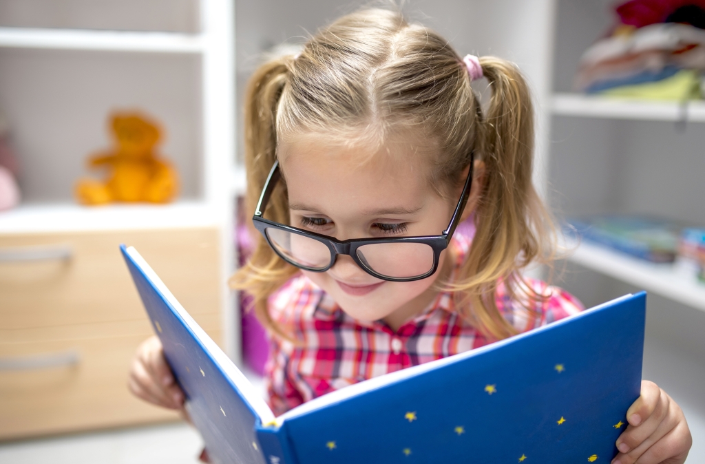 Ein Mädchen liest ein Buch. Lesen eröffnet die Möglichkeit Neues zu lernen. Lesekompetenz zu Fördern, ein Hauptanliegen in der Grundschule.